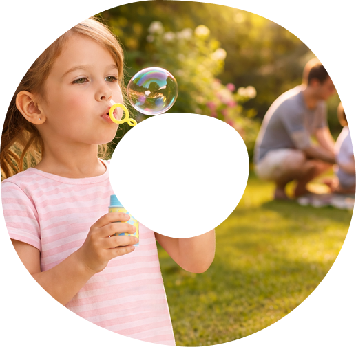 Child playing outside with family nearby